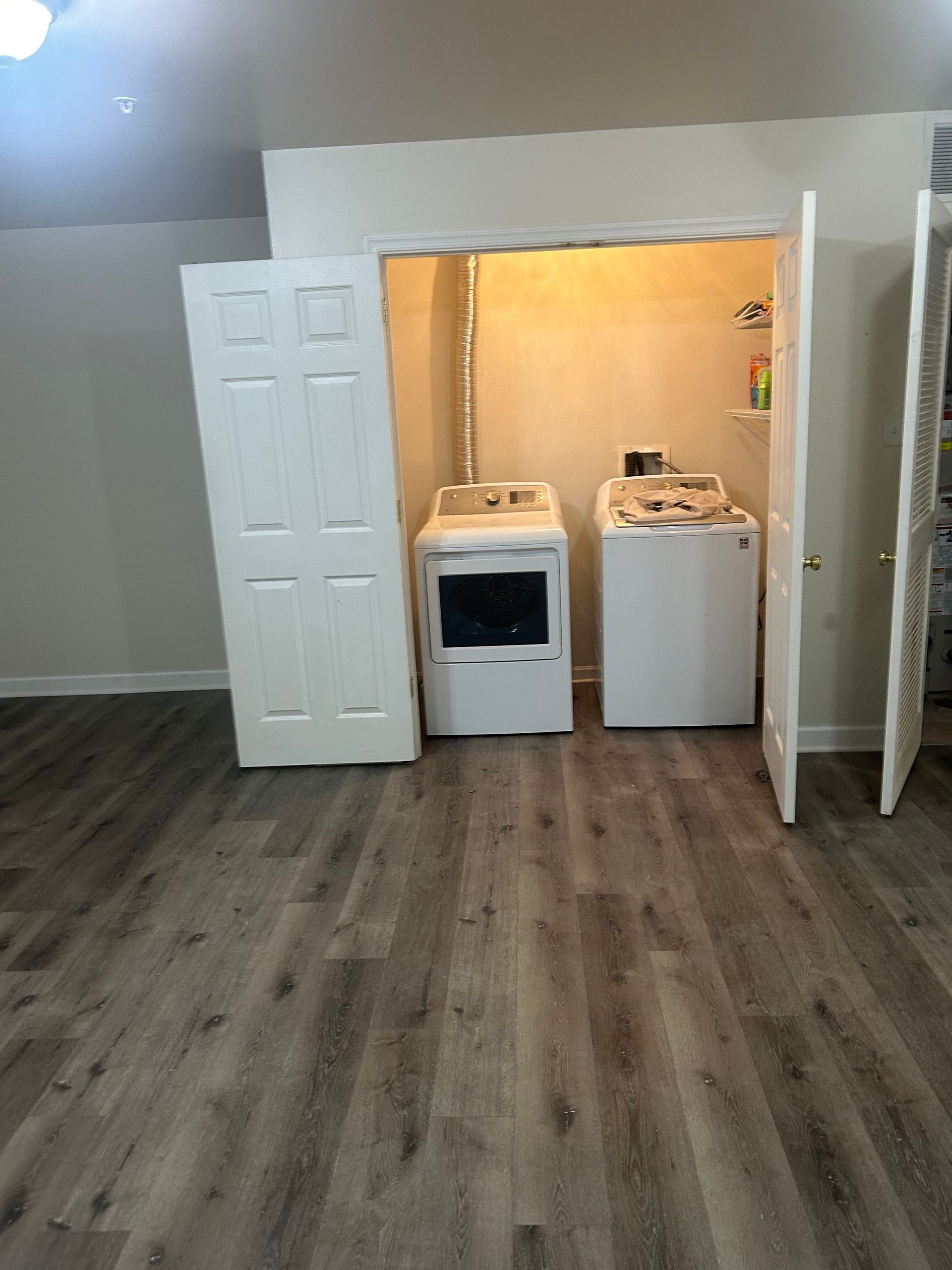 Laundry area with washer and dryer in a doorway, white doors, and wood-look flooring