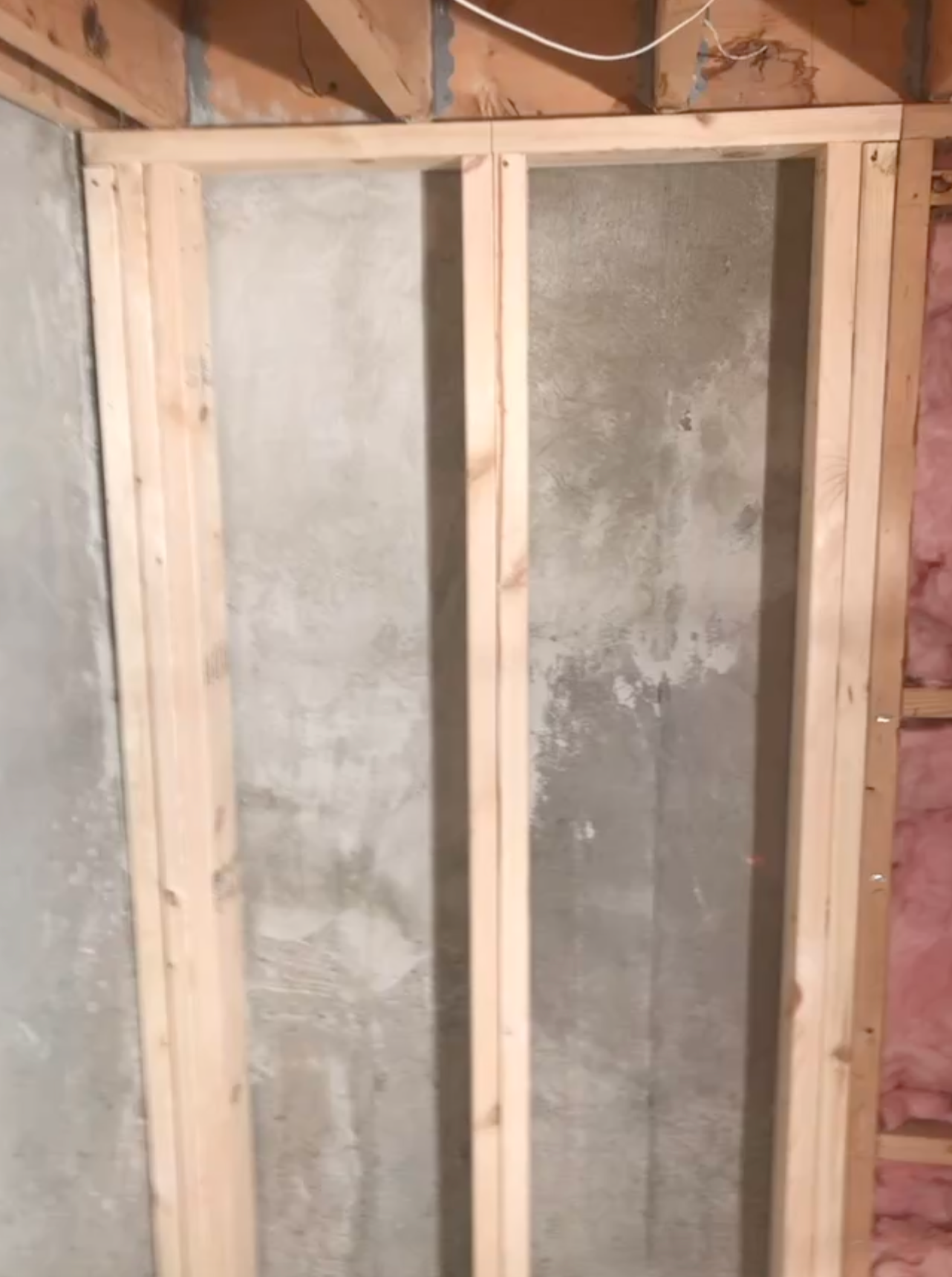 Framed shower enclosure with frosted glass panels and exposed wood framing under construction
