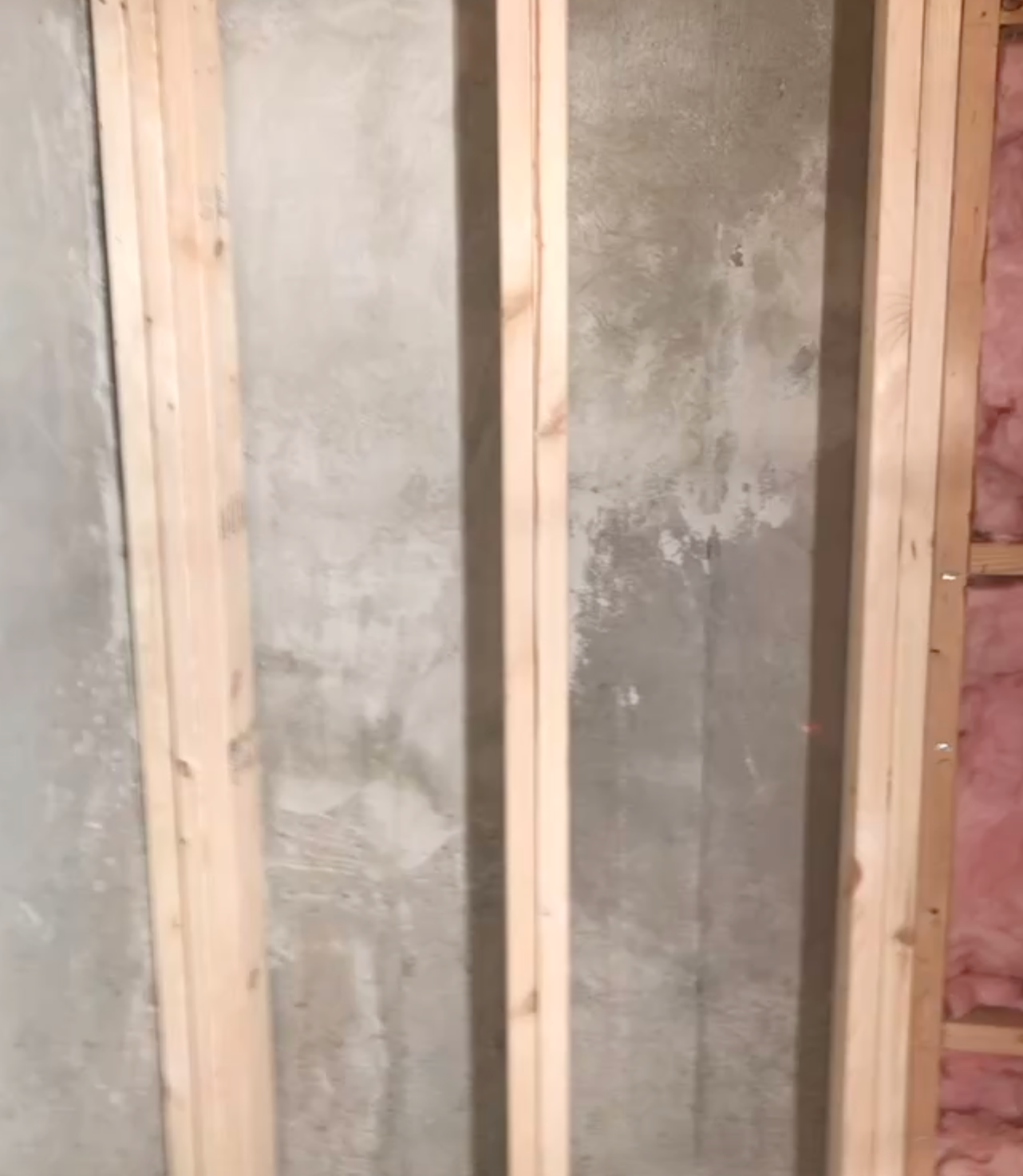 Exposed wall studs framing unfinished concrete wall panels inside a construction site.