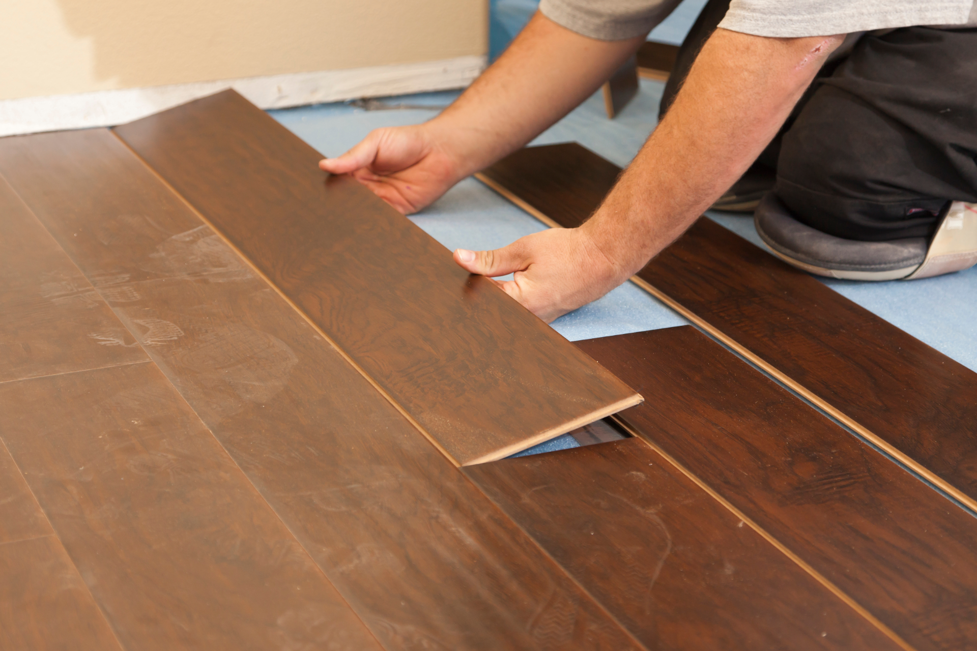 Person installing dark wood flooring in a room