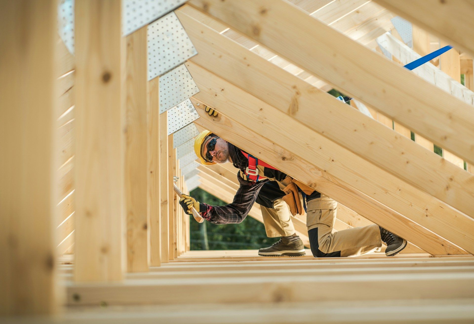 Worker assembling wooden house frame with beams and trusses on a construction site