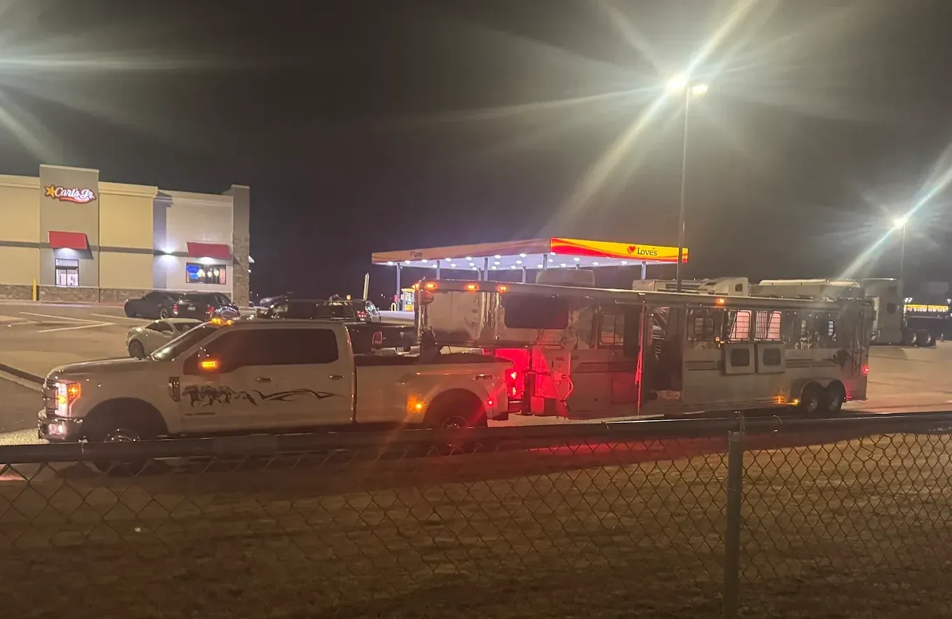A truck is towing a trailer in a parking lot at night.