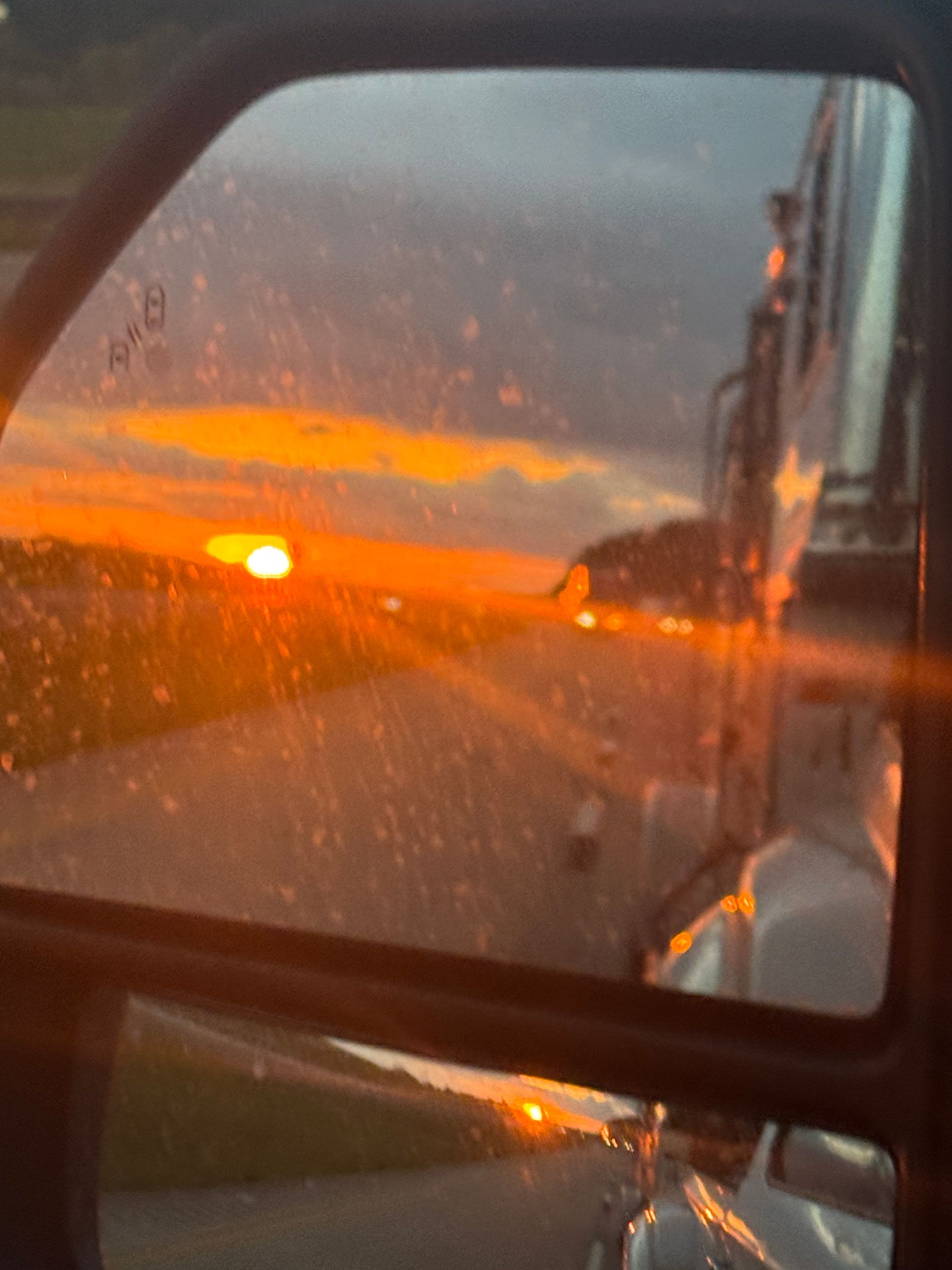 A close up of a car window with a sunset in the background.
