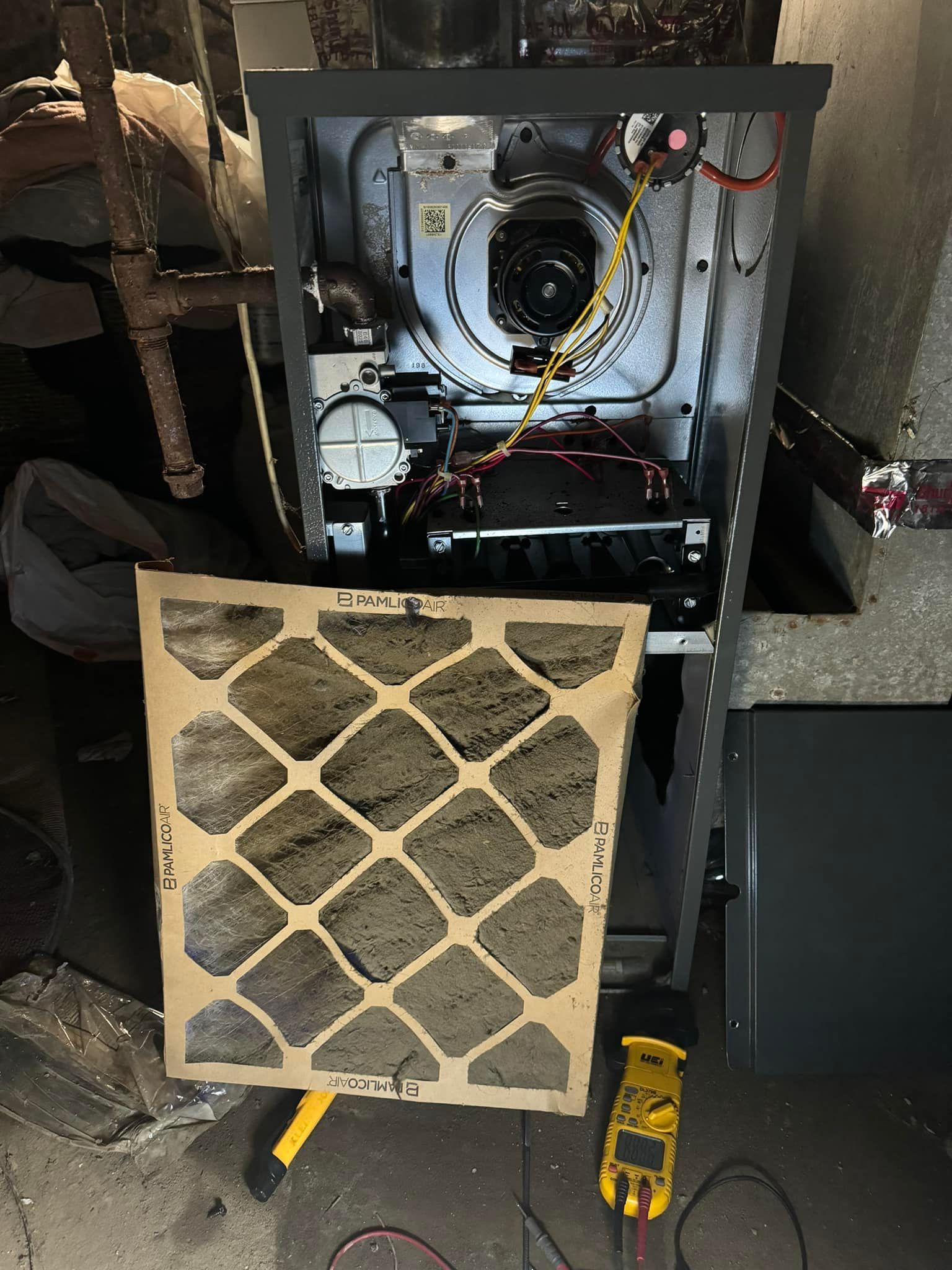 Open furnace with removed filter panel showing internal components and wiring