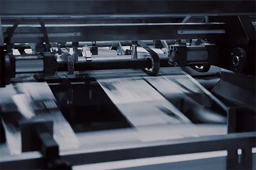 High-speed printing press moving paper sheets through a machine