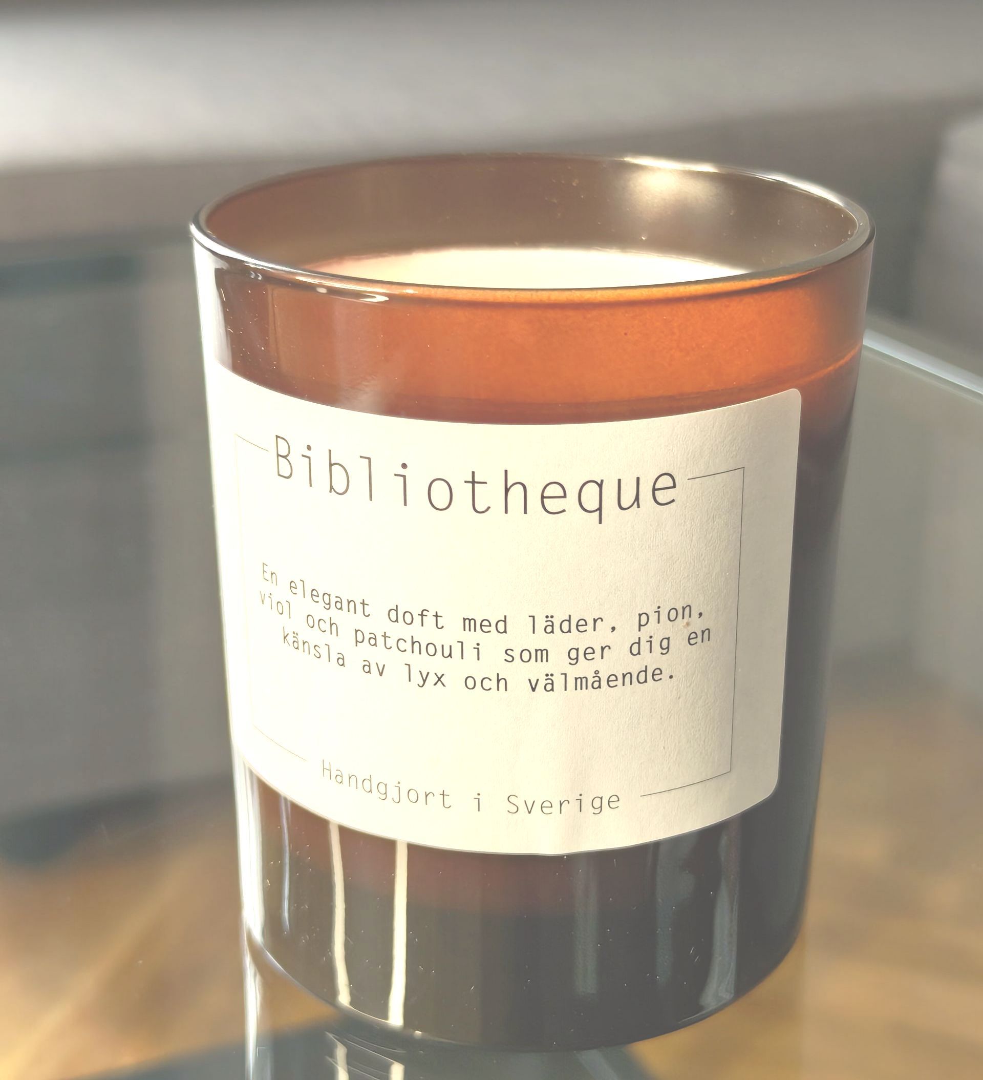 Black candle in a glass jar with a white label on a wooden surface
