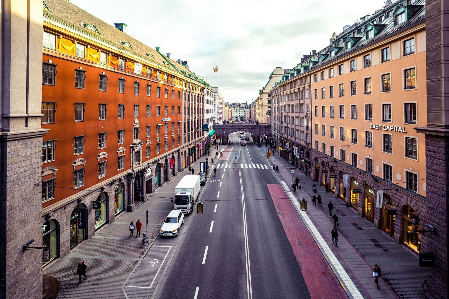 Aerial view of a wide city street lined with orange and beige apartment buildings.
