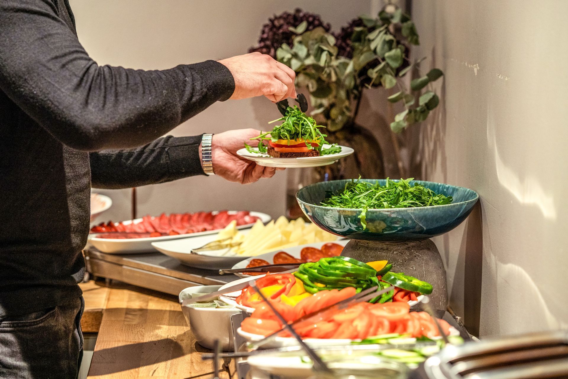 Person serving salad at a buffet table with assorted colorful dishes