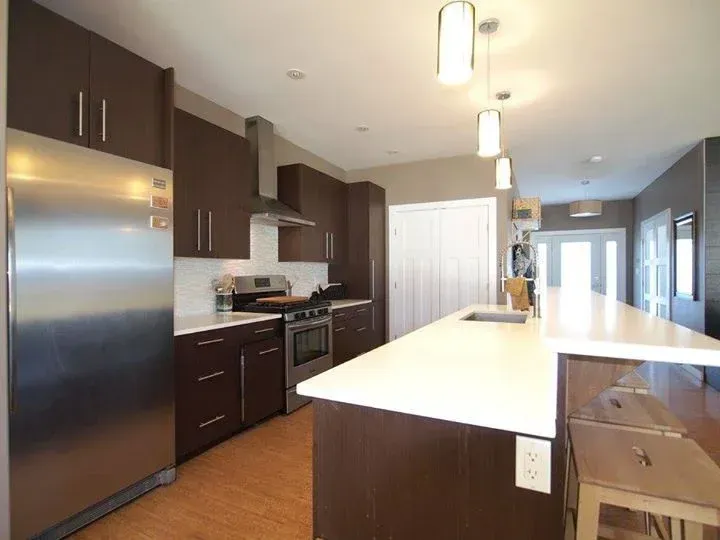 Modern kitchen with dark brown cabinets, stainless steel appliances, and white countertops.