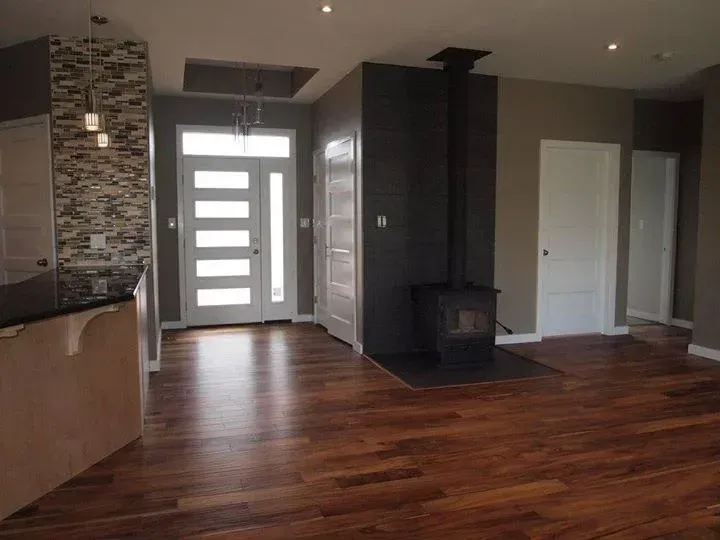 Interior view of a home with hardwood floors, a white door, fireplace, and neutral-colored walls.