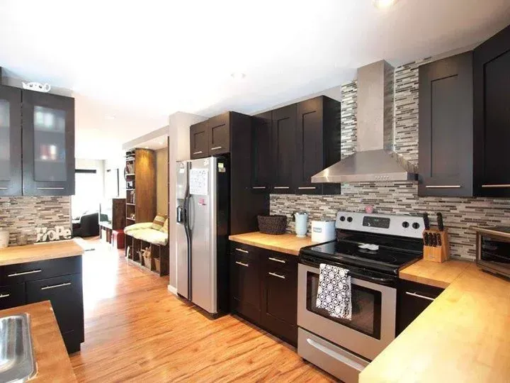 Modern kitchen with dark cabinets, stainless steel appliances, and wooden countertops.
