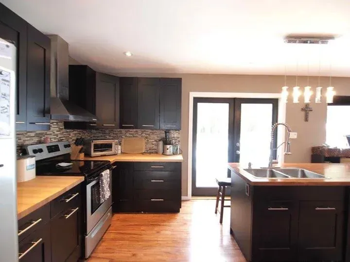 Dark cabinetry kitchen with wood counters, stainless steel appliances, and French doors.