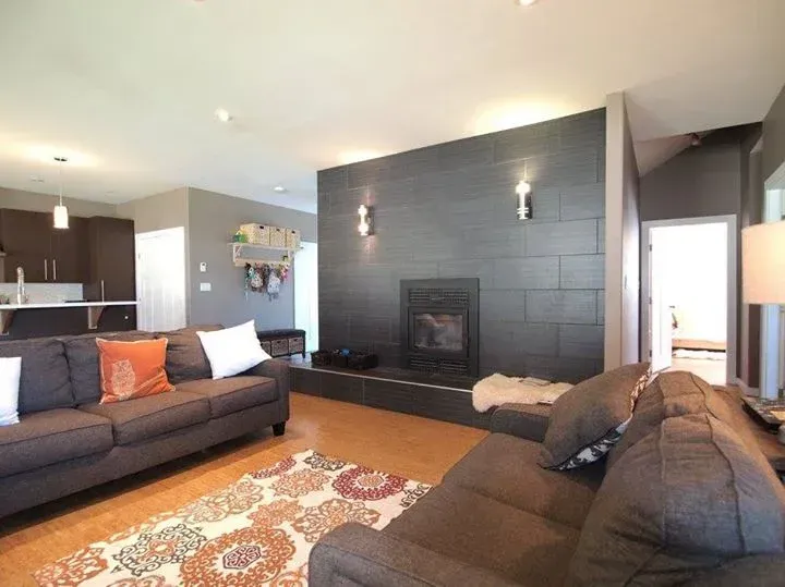 Spacious living room with a gray sectional sofa, fireplace, and open kitchen.