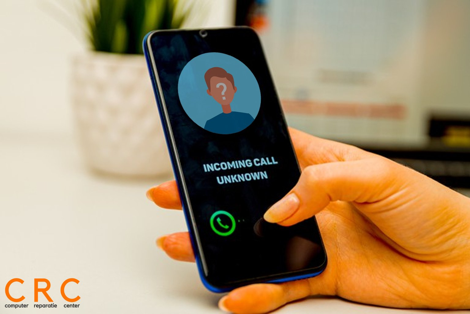 Een persoon houdt een mobiele telefoon vast waarop inkomend gesprek onbekend staat.