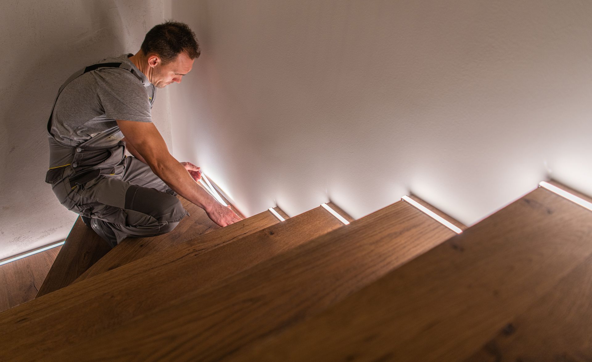 Electrician installing LED lighting on wooden stairs