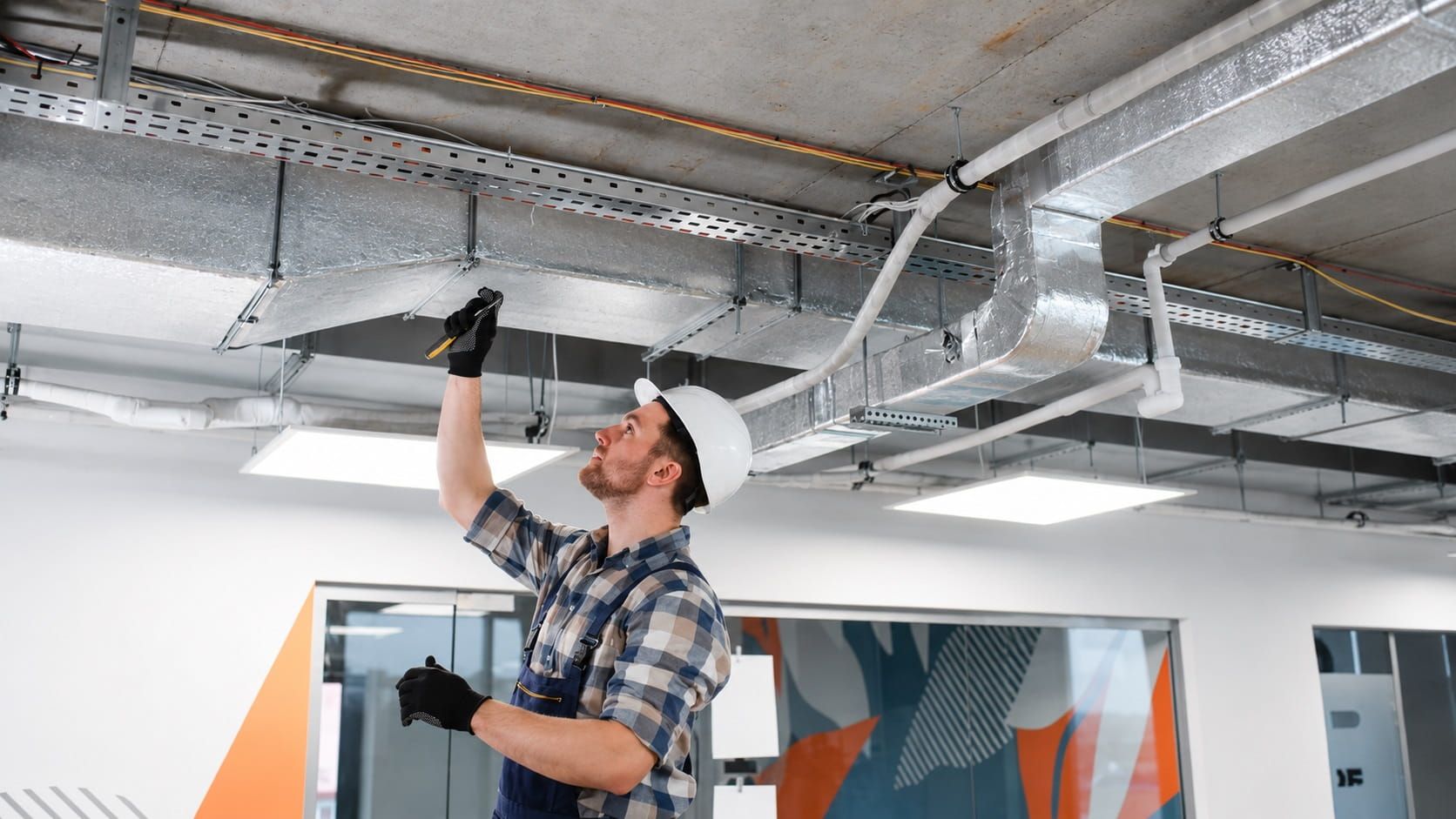 Electrician inspecting ceiling wiring during a commercial electrical inspection