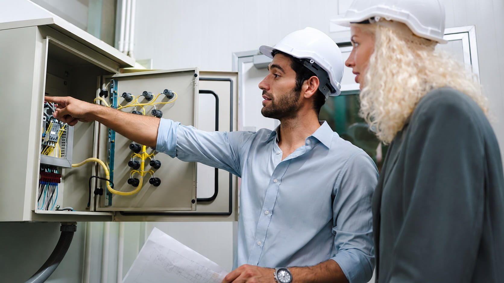 Electrician reviewing a commercial electrical panel with a client