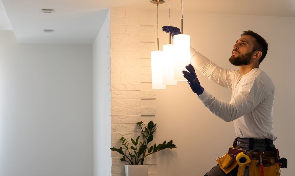 Technician adjusting hanging light fixture