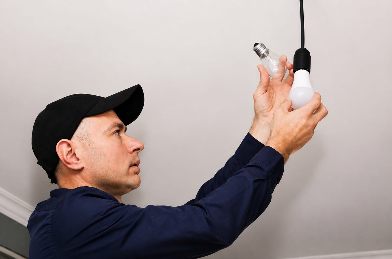 Electrician replacing a light bulb during a service call
