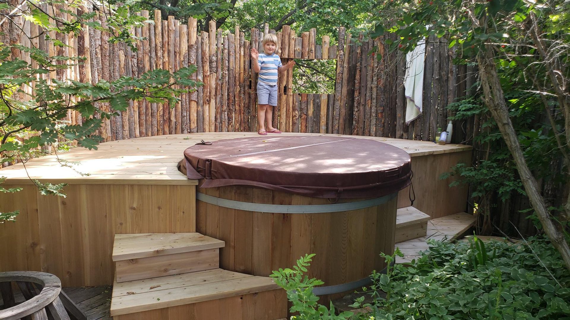 A Little Girl is Standing Next to a Wooden Hot Tub