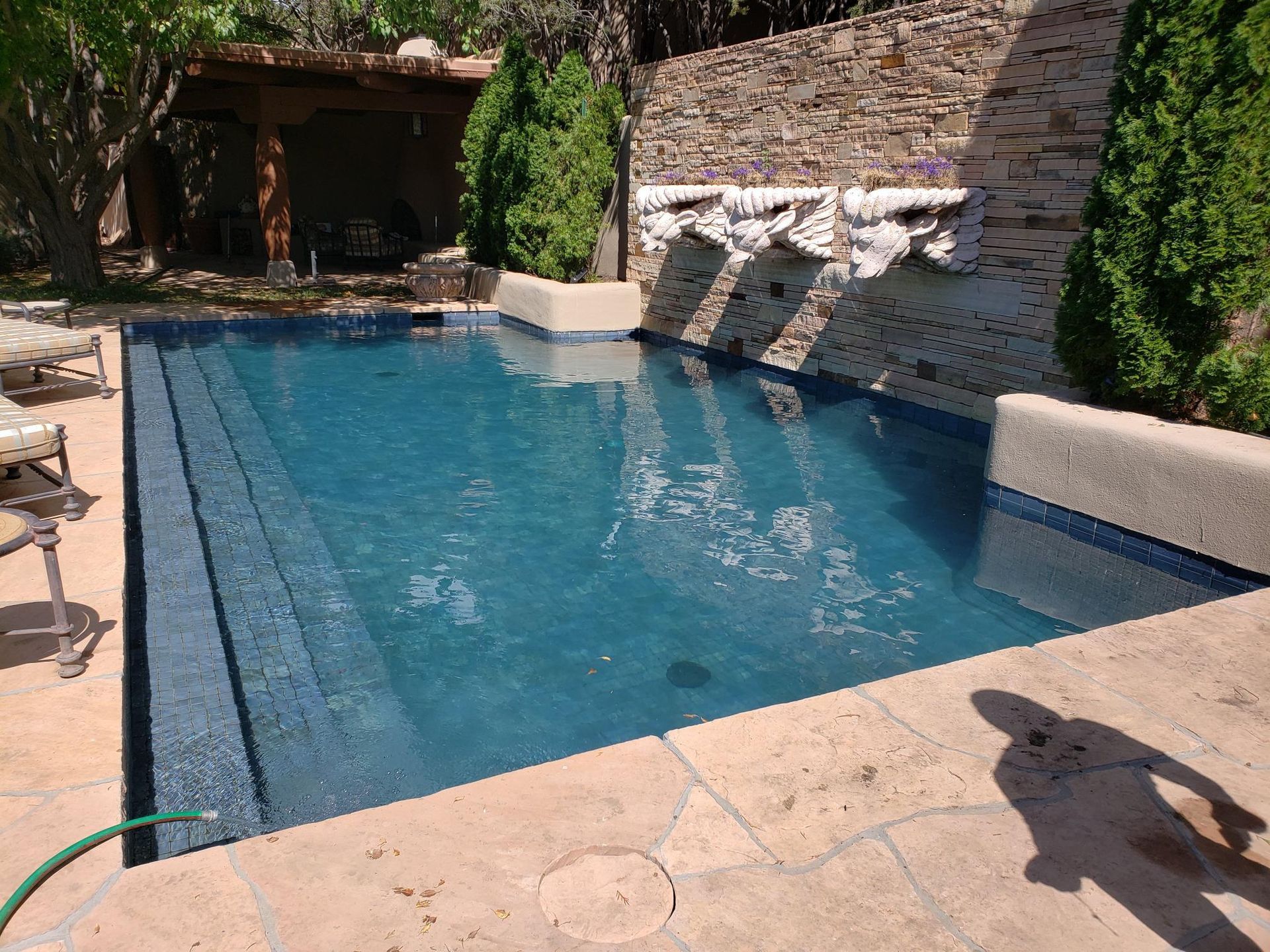 A large swimming pool with a waterfall in the backyard.
