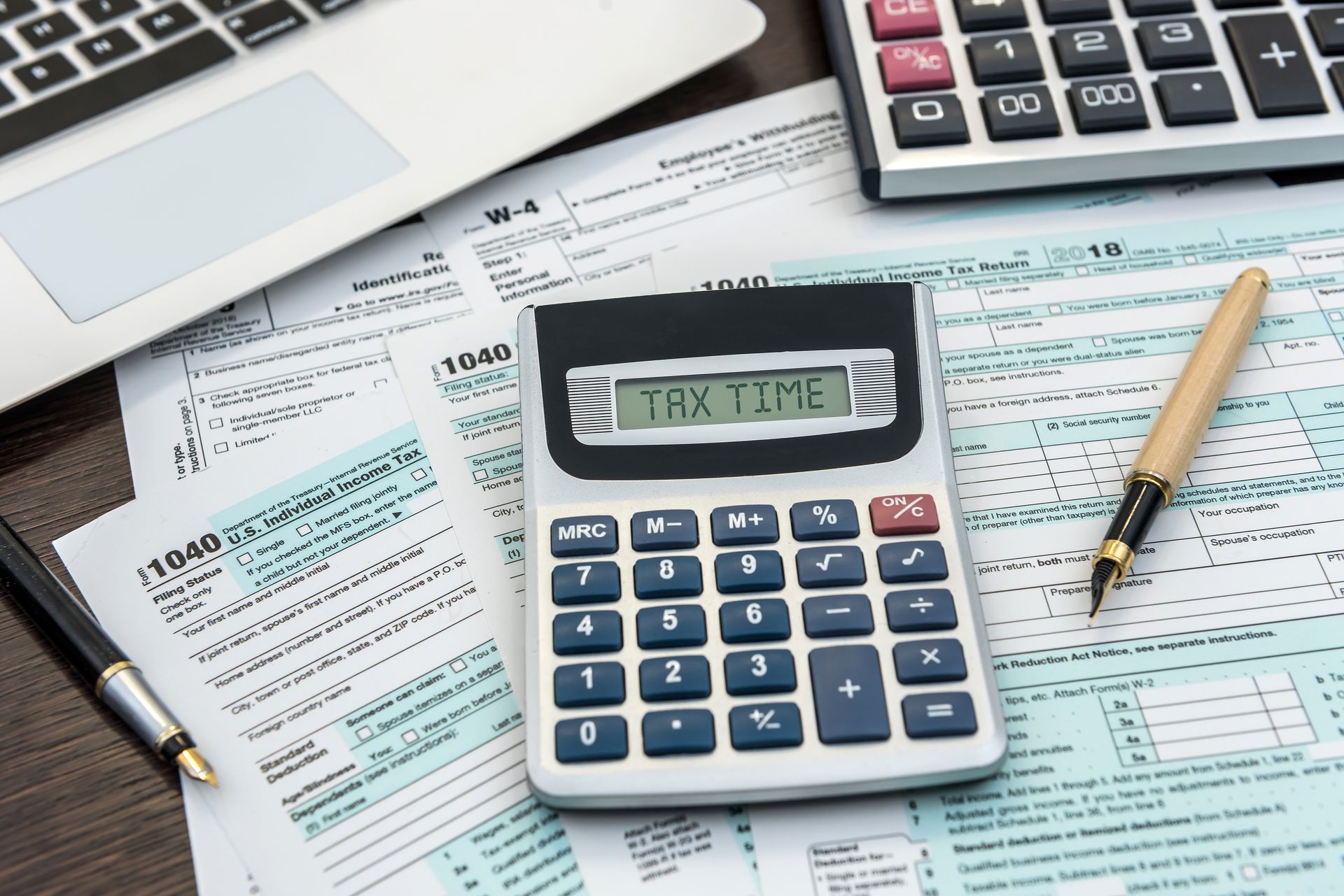 A calculator is sitting on top of a pile of tax forms.