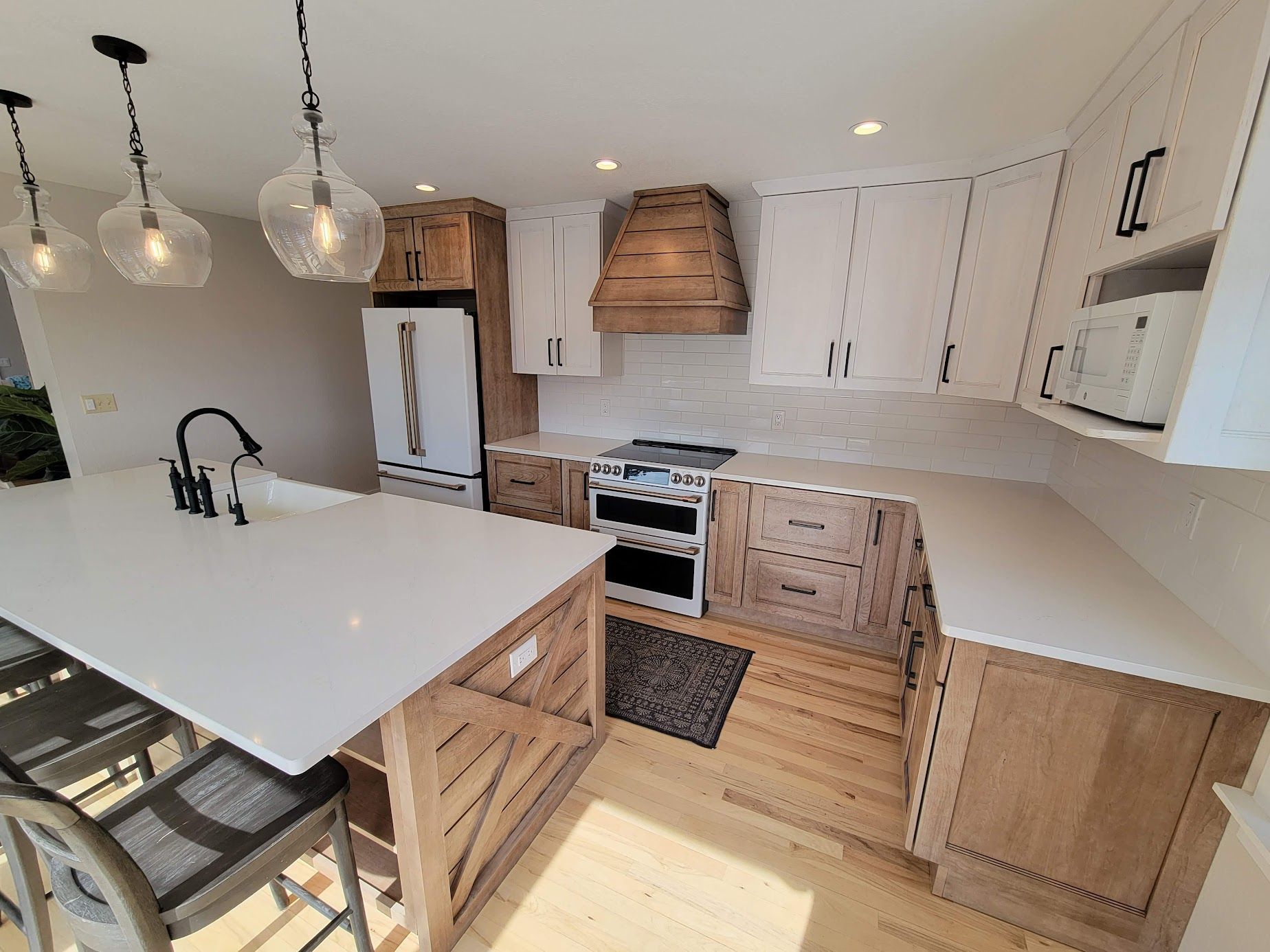 Bright modern kitchen with white island, wood cabinets, pendant lights, and stainless appliances