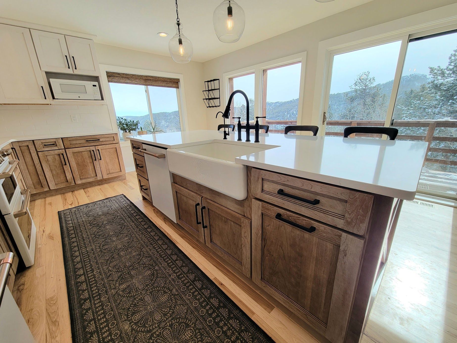Modern kitchen with wood cabinets, large island, pendant lights, and bright windows overlooking a snowy view