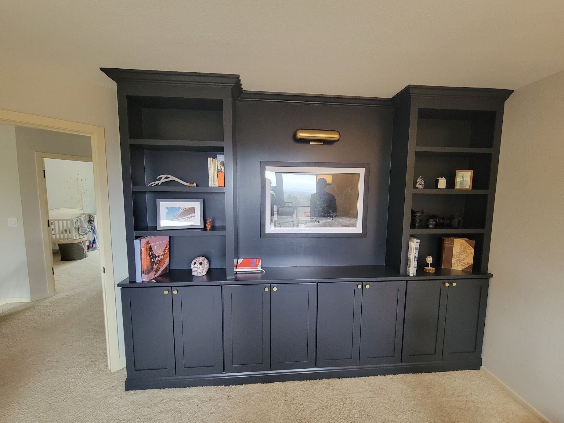 Black built-in wall unit with shelves, cabinets, and a centered mirror in a beige room