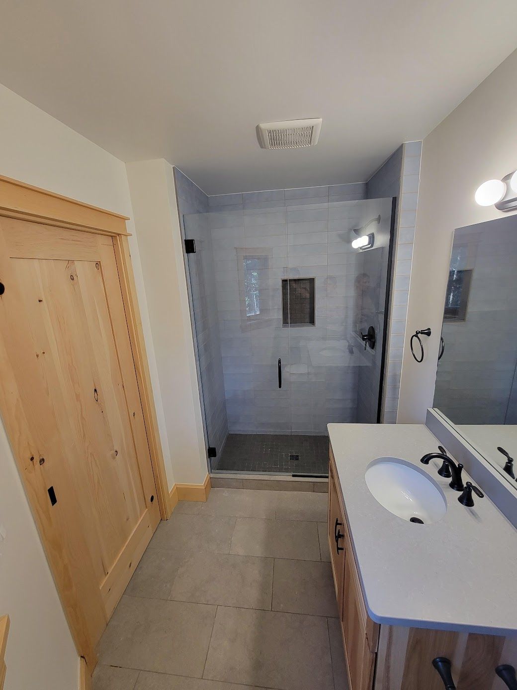 Bathroom with walk-in shower, vanity sink, mirror, and wooden closet doors.