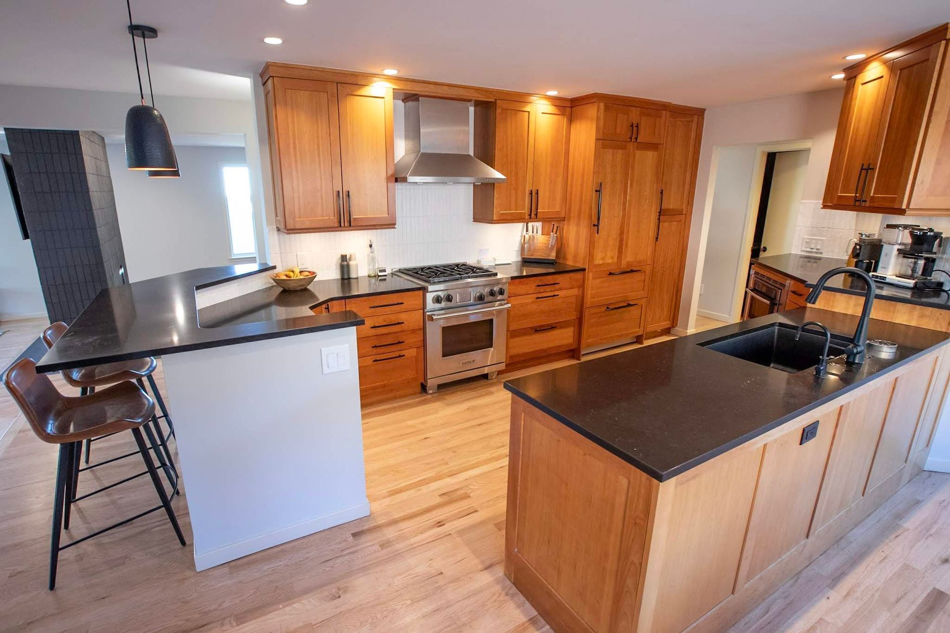 Modern kitchen with wooden cabinets, black countertops, and stainless steel appliances
