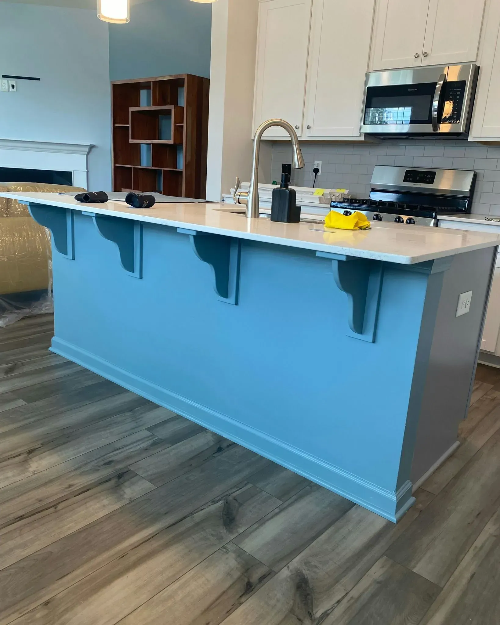 Modern kitchen with blue island, white countertops, and stainless steel appliances