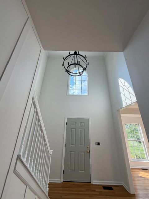 Entryway with staircase, gray front door, high window, and hanging light fixture.