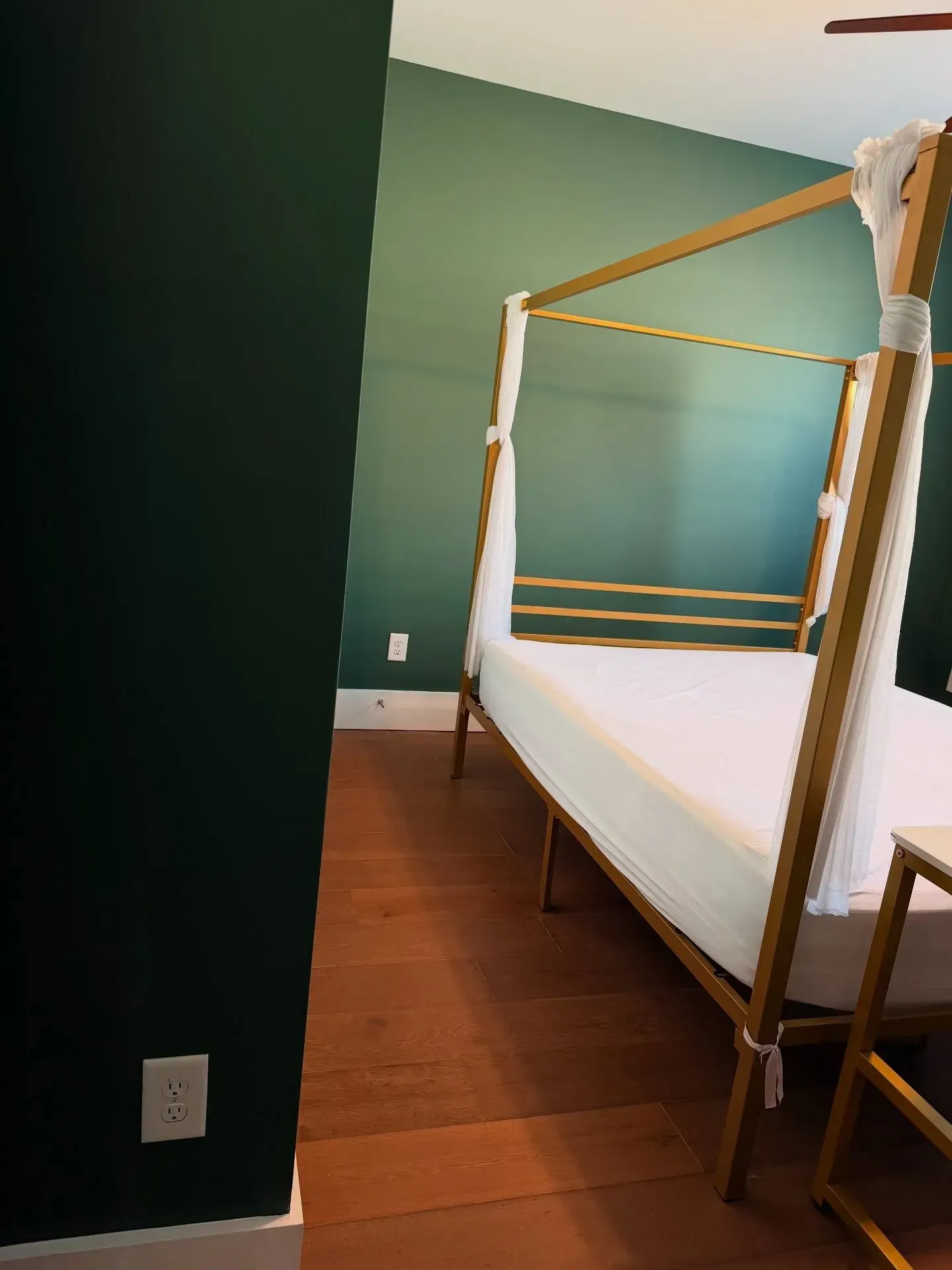 Small bedroom with a four-poster bed, green walls, and hardwood floor.