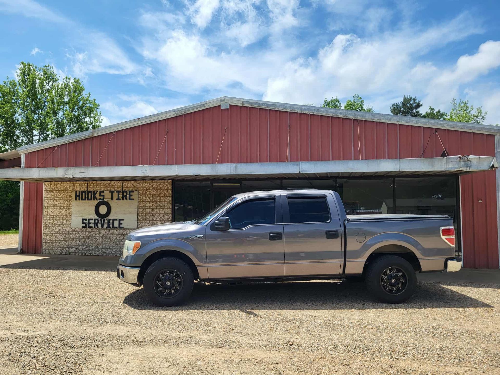Silver pickup truck parked in front of a red-roofed service building with a sign for online order service.