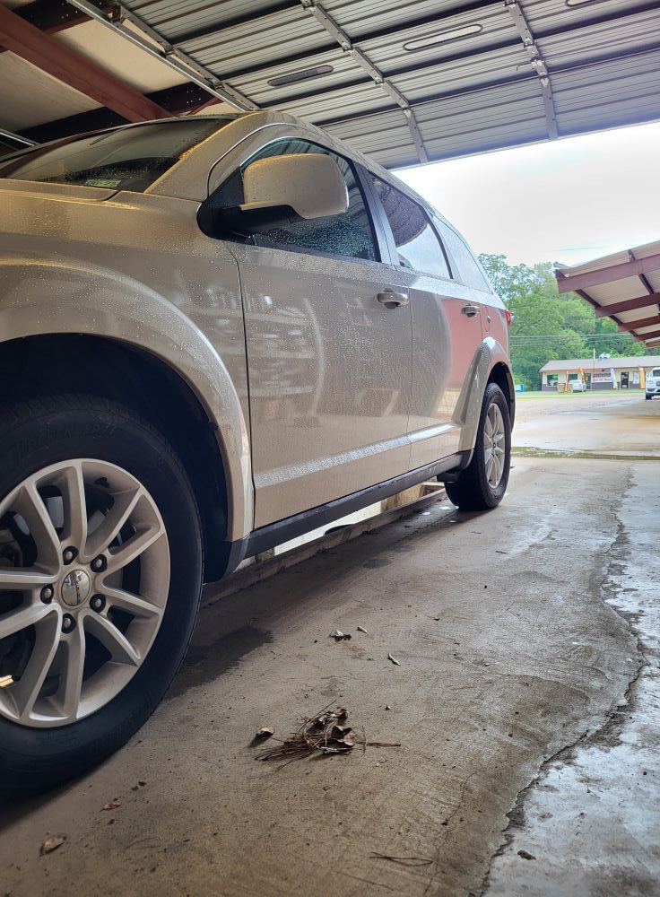 Silver SUV parked in a covered garage, low-angle view of front side and wheel.