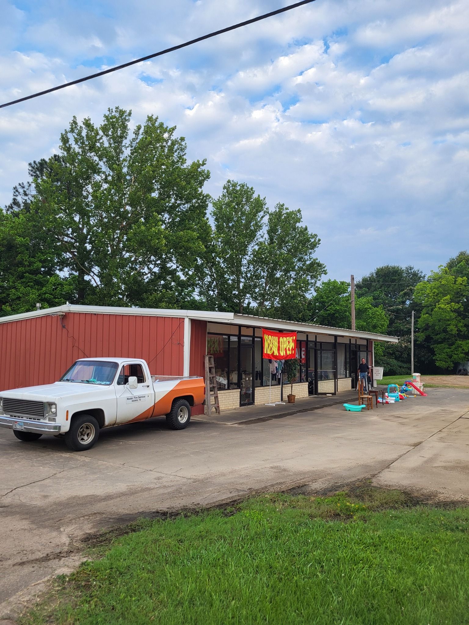 White pickup truck parked by a small roadside shop with a red roof under a cloudy sky