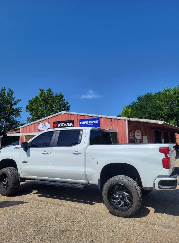 White pickup truck parked in front of a red building with signs under a clear blue sky