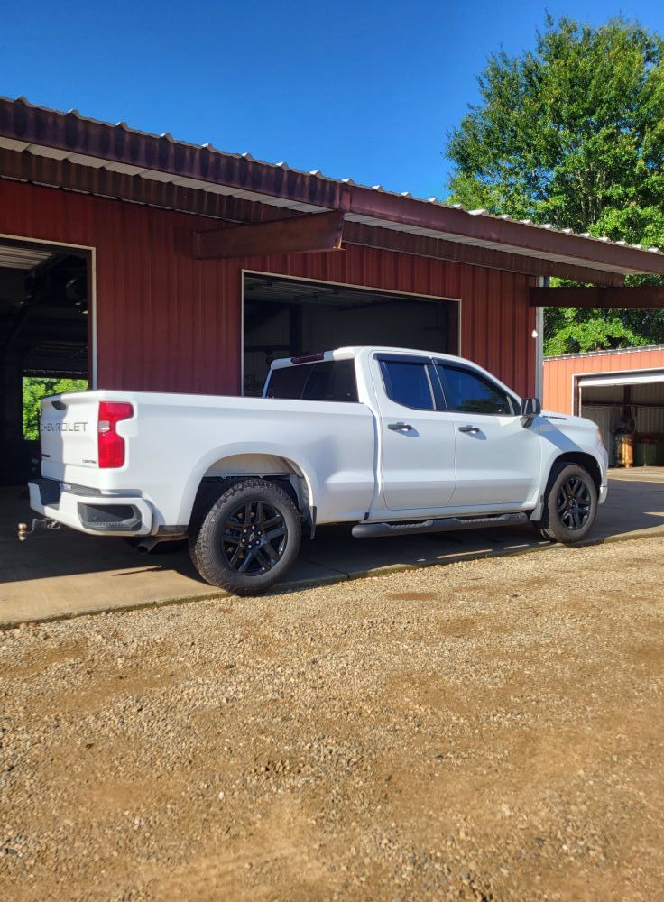 Silver pickup truck parked beside a red garage on a sunny day