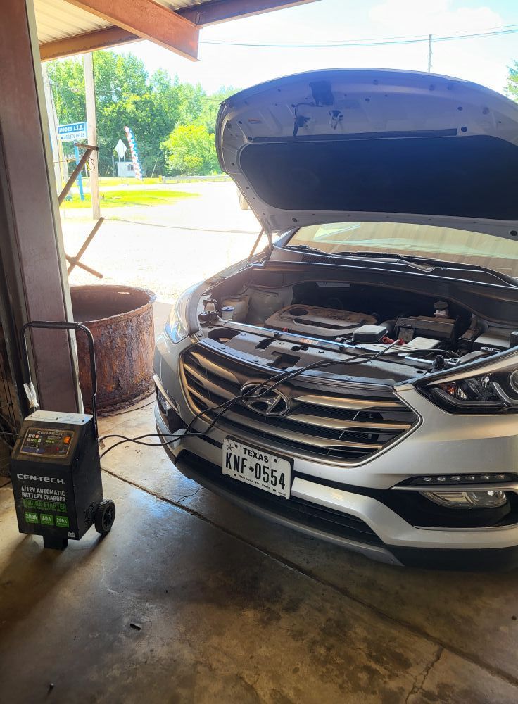 Silver Hyundai with hood open in a garage, showing the engine bay.