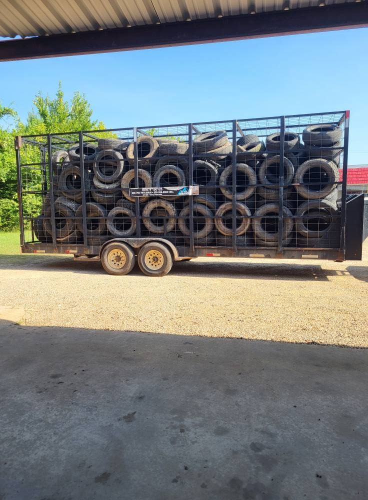 Trailer loaded with stacked tires under a covered outdoor structure