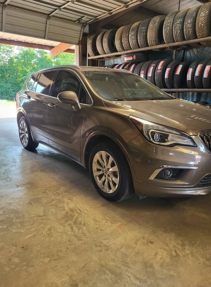 Brown SUV parked in a tire shop garage with stacked tires along the wall