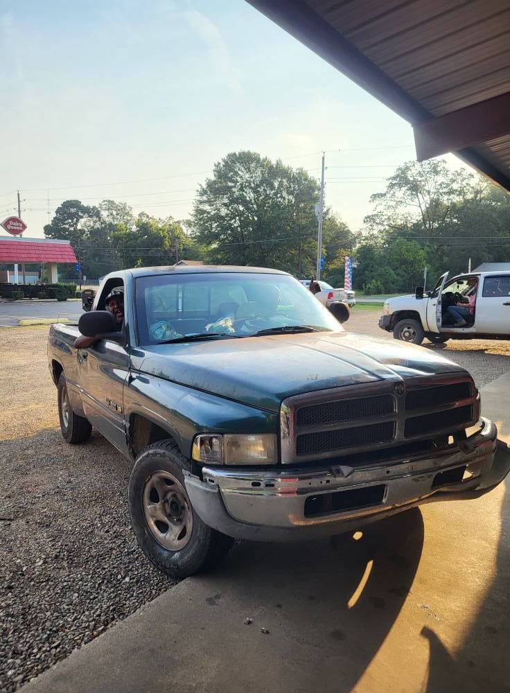 Black pickup truck parked on gravel under a covered area at sunset