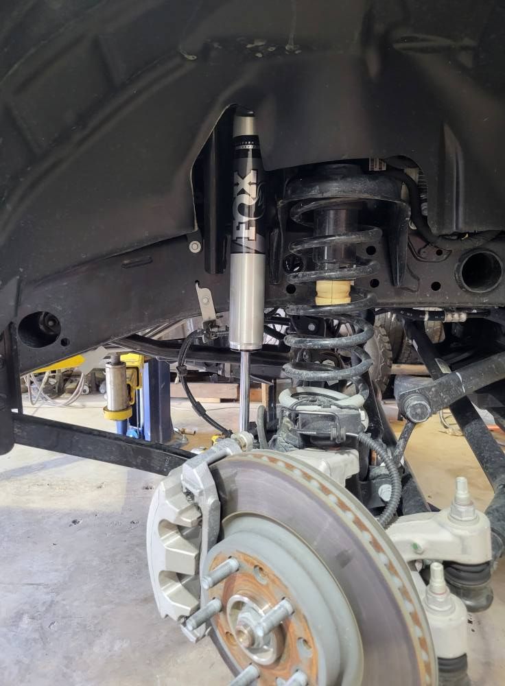 Front wheel well with exposed suspension, brake rotor, and shock absorber on a vehicle lift