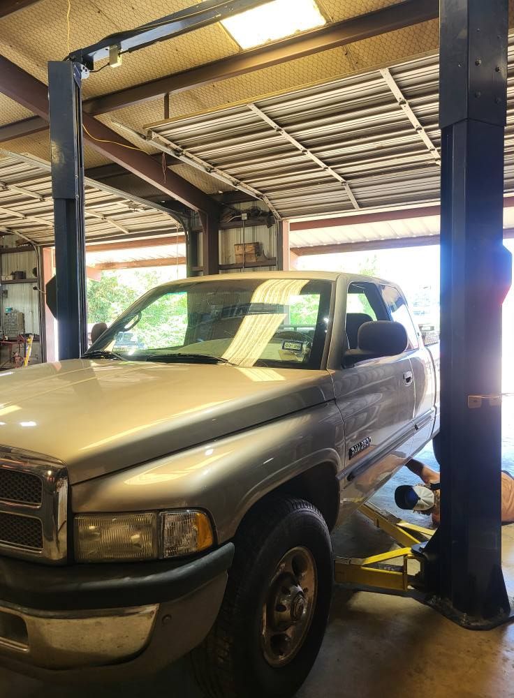 Silver pickup truck on a lift inside a garage or auto repair shop