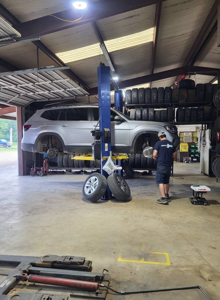 Auto repair shop with SUV on a lift and mechanic standing nearby under bright overhead lights
