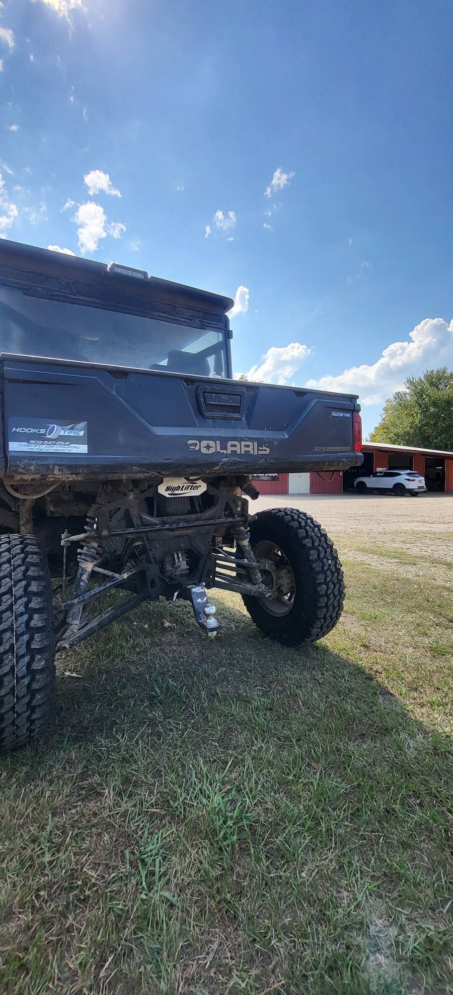 Lifted black pickup truck parked on grass under a blue sky.