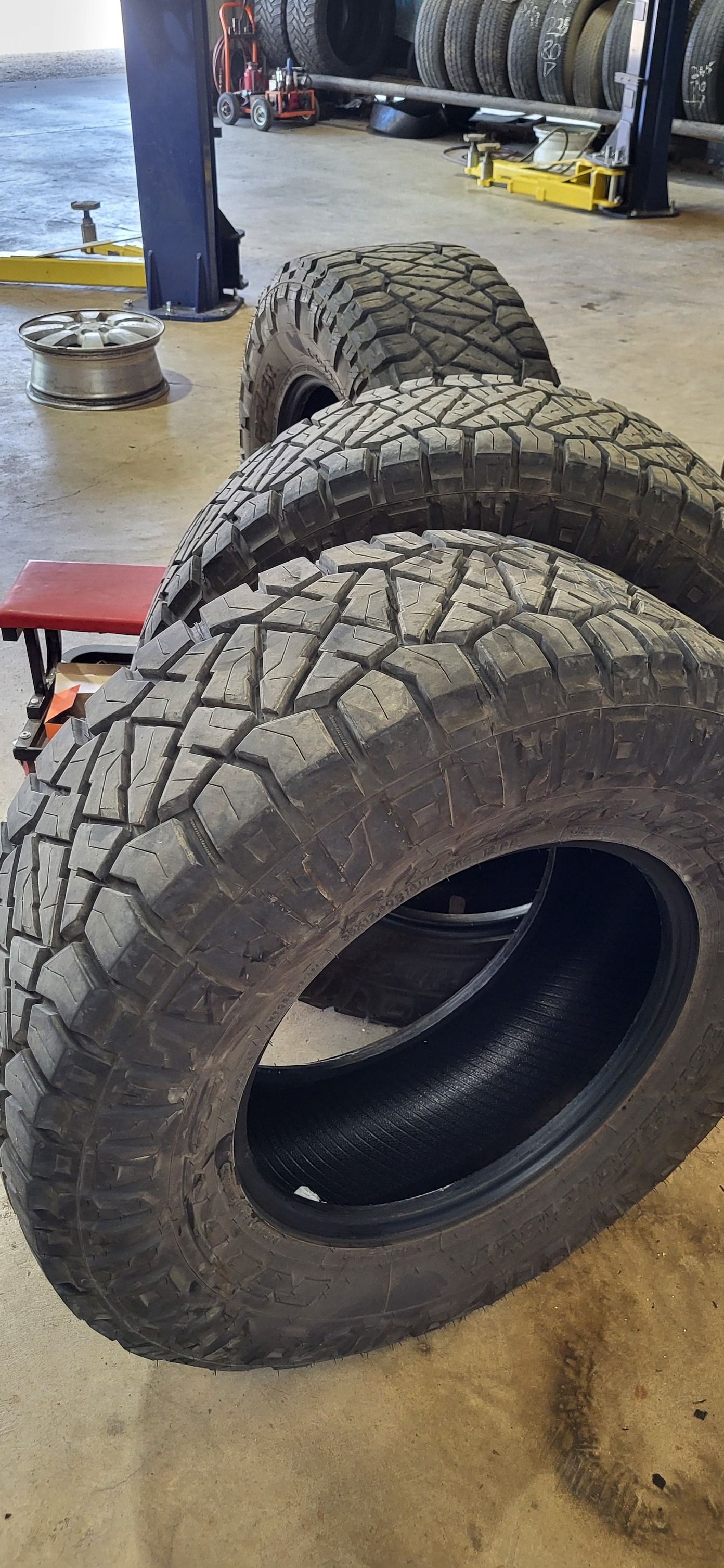 Stacked black off-road tires in a workshop garage.