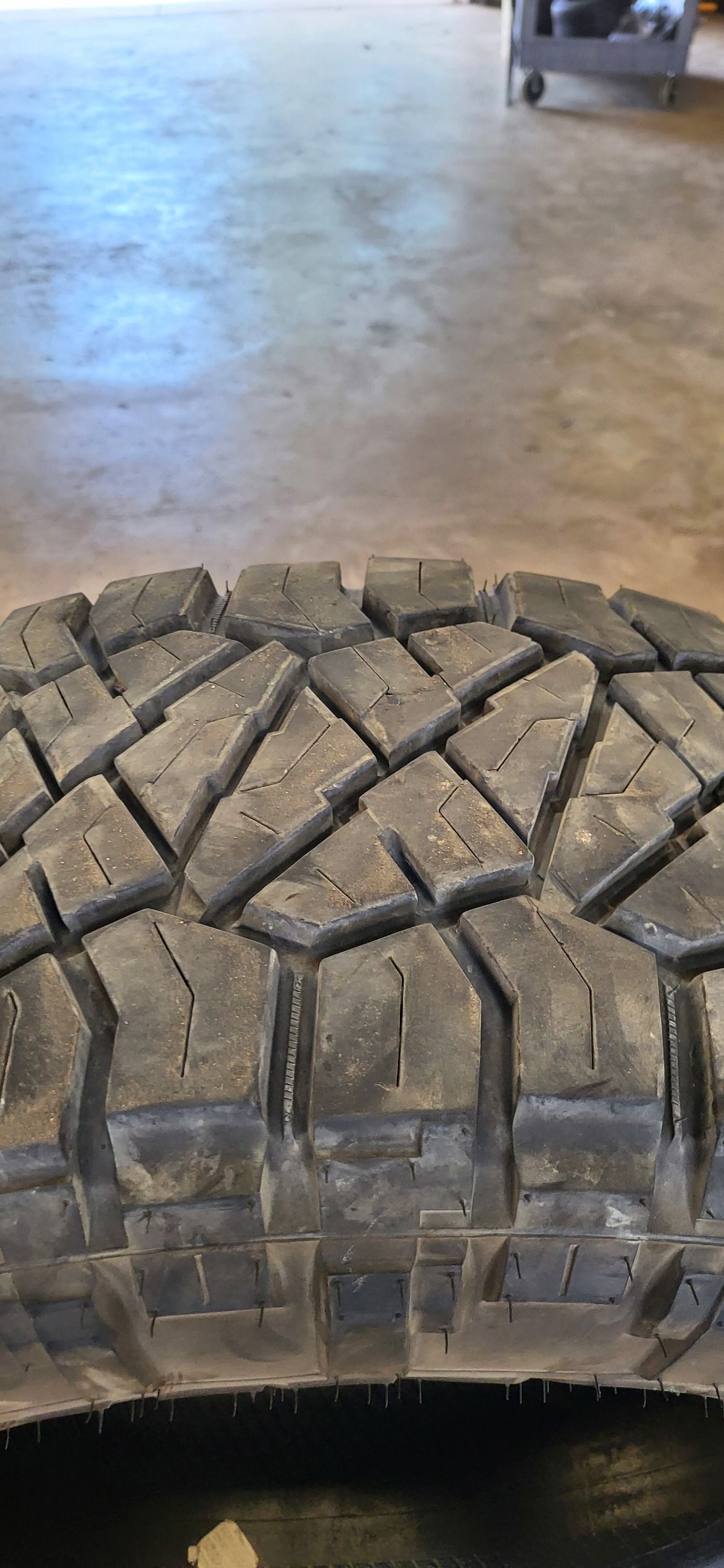 Close-up of a rugged off-road tire tread on a garage floor
