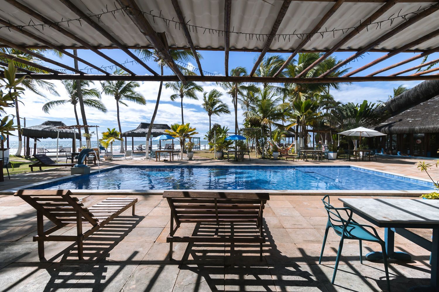 Uma grande piscina cercada por cadeiras e mesas com vista para o oceano.